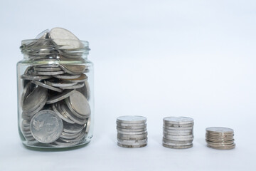 Indonesian Rupiah coins in glass jar and stacked coins with white background