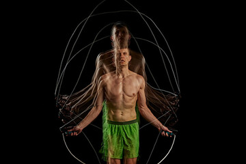 Essence of sport and athleticism. Muscular man in motion, training, doping cardio, jumping rope against black background with stroboscope effect. Concept of sport, active and healthy lifestyle - obrazy, fototapety, plakaty