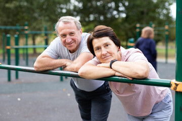 Elderly man and woman posing in open-air sports bars complex - 792915119
