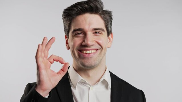 Positive businessman makes OK hand sign, okay gesture. Happy office guy on white