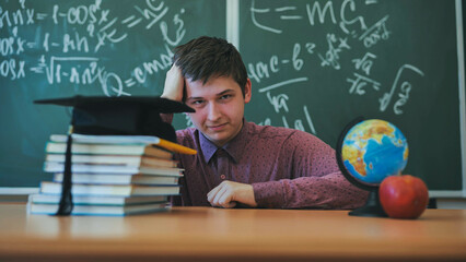 Portrait of a high school student against a background of blackboard, globe and books with cap.