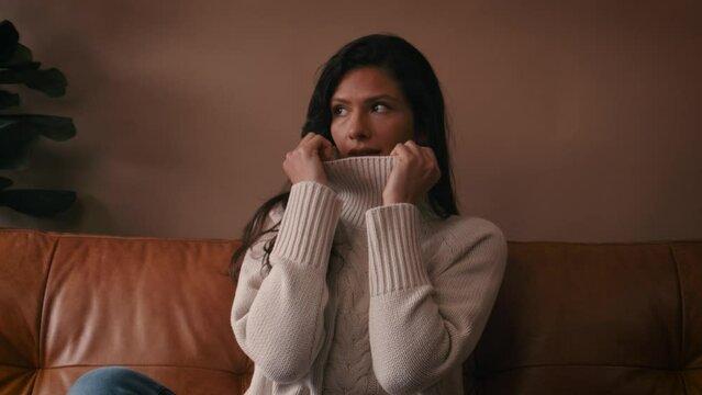 Beautiful attractive woman sitting on sofa , flirting , posing and looking into and away from camera. Fashion concept. Drinking coffee, cosy jumper