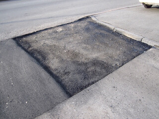 Asphalt pothole road patching repair, rectangular new asphalt patch street renewal.