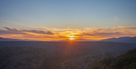 Fototapeta na wymiar Sunrise over the green hills of the shrub savanna in southern Africa.
