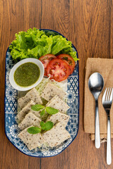 A plate of Vietnamese pork sausage with lettuce, tomatoes, and mint leaves.