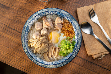 A bowl of rice noodles with pork and vegetables.