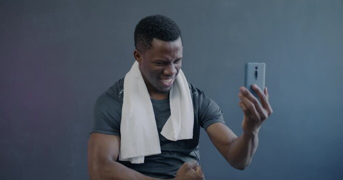 Slow motion of playful African American sportsman taking selfie with smartphone camera on purple background. Photo and active lifestyle concept.