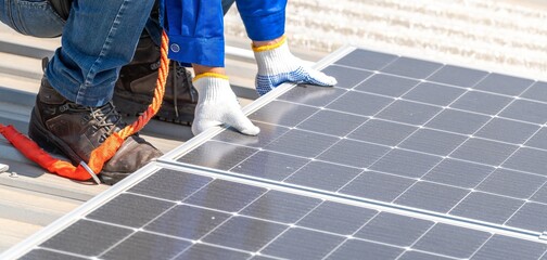 A worker installing solar panels on a roof.