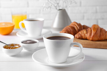 Fototapeta na wymiar Cup of coffee, jam and croissants on white wooden table. Tasty breakfast