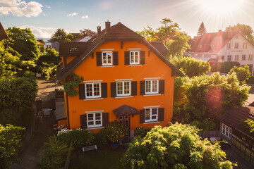 Captured from above, the sunny tangerine-colored house with traditional windows and shutters stands out against the lush greenery of the suburban neighborhood, 