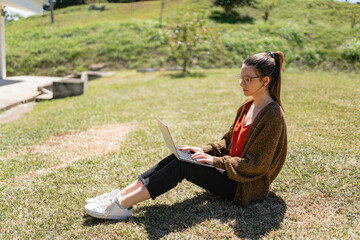 Focused female freelancer using laptop to work remotely in park