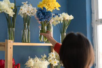 female florist placing a vase of flowers on a shelf while working in her flower shop.