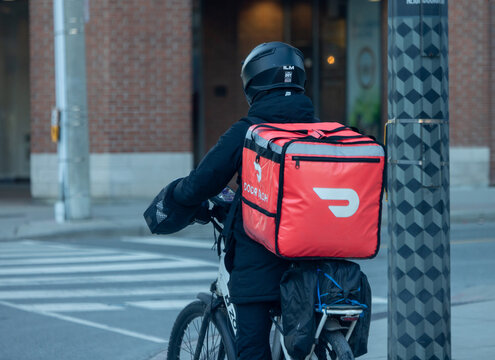 Toronto, Canada, January 4, 2024; A food delivery courier on an  bicycle, with no logo on back pack on a downtown street