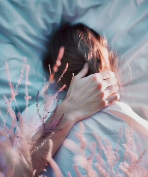 Young woman lying in bed and holding her hair. Blurred background.