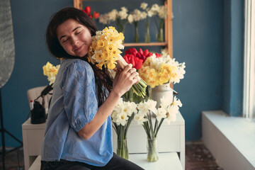 Portrait of a happy woman with a bouquet of flowers in her hands. Florist working in a flower shop