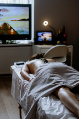 Woman enjoying hot stone massage at spa salon. Professional masseur making stone therapy. Relaxing...