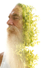 A portrait of a bearded man merging into green tree leaves in a double exposure