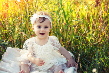 Happy little girl sitting in a flower field on a sunny day
