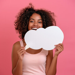 Happy excited young african american woman holding blank speech bubble for thoughts isolated on pink studio background. Girl with empty word cloud offering space for text
