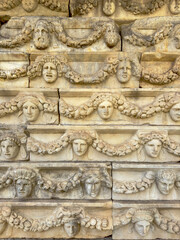 Vertical close-up of a stone frieze depicting theater masks and garlands from ancient Aphrodisias in Aydın, Turkey.