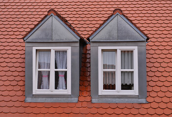 Two windows in the loft - red tiled roof - White curtains