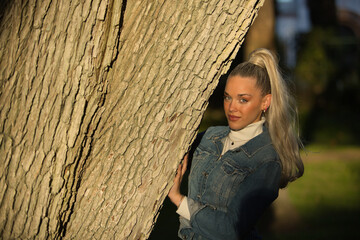 Woman, young, pretty, blonde, with blue eyes and denim dress, playing hide and seek behind the...