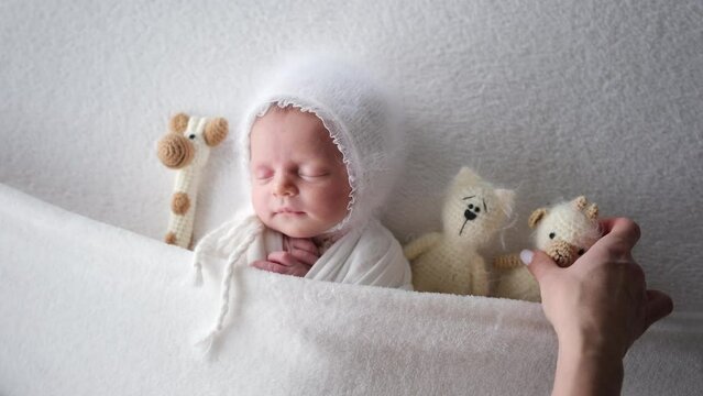 Solicitous Mother Adding A Knitted Toy In Bed To Her Sleeping Newborn Baby Girl