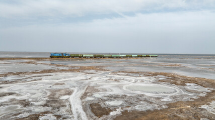 a train travels across a salt lake to transport salt in the area of Lake Baskunchak on a spring day