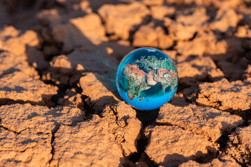Miniature glass globe on heat-cracked clay in the desert