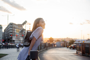 A  beautiful teenage girl walks around the city against the background of sunlight, the model...