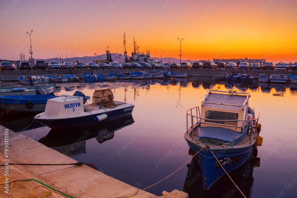 Wall mural sozopol, bulgaria - 03 sep 2019: small fishing boats in the harbor at dusk. cloudless sky reflecting