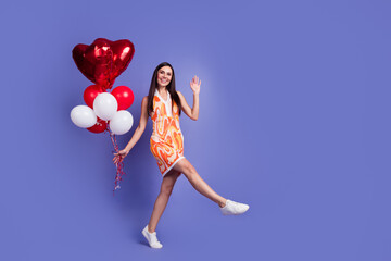 Full size photo of pretty young woman hold balloons empty space ad wear dress isolated on violet color background