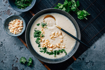 Spicy and creamy cauliflower and coconut soup with cilantro and macadamia nuts