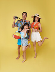 Happy fun asian family vacation portrait. Father, mother and daughters enjoying summer beach isolated on yellow studio background.