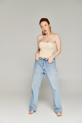 A woman exudes confidence in jeans and tank top, striking a pose.