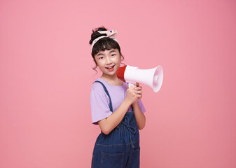 Asian little girl standing and holding megaphone isolated on pink background, Speech and announce...