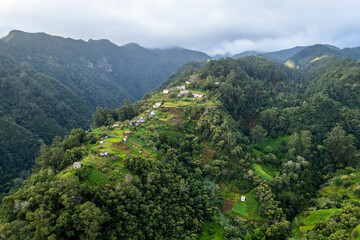 Fototapeta na wymiar Madeira Island landscape, small village on hills and green lush forest. Aerial drone view. Portugal travel.