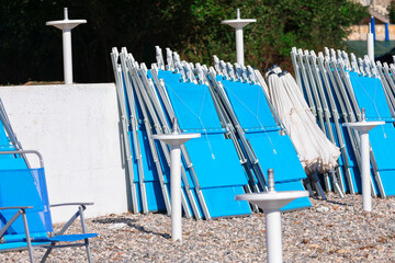 Row of beach chairs with umbrellas on the beach in the summer. Empty beach chairs and umbrellas on a pebble beach