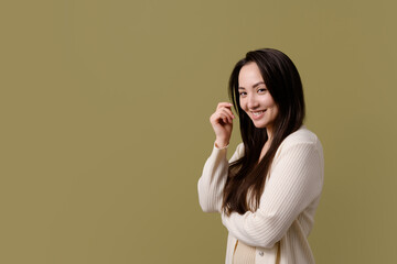 Smiling long haired asian woman looking at camera isolated on green 