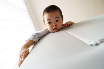 Sleepy Asian baby boy climbing playpen to looking after waking up at home