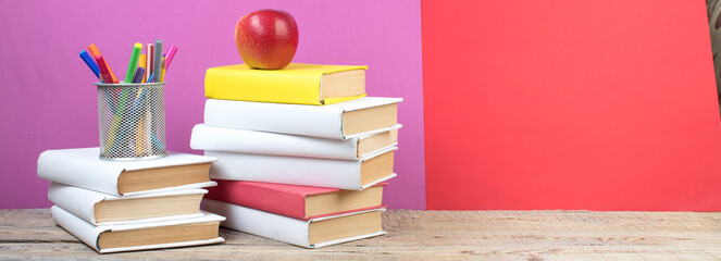 Books stacking. Books on wooden table and red, purple background. Back to school. Copy space for ad text. panorama, banner.
