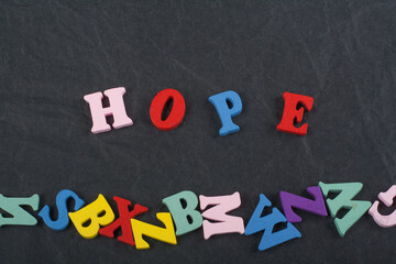 HOPE word on black board background composed from colorful abc alphabet block wooden letters, copy...