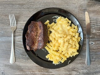 steak with macaroni and cheese on a plate