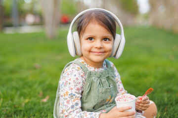 little girl with headphones listening to music and dancing in the park.