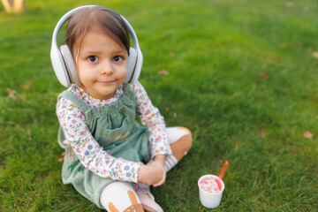 little girl with headphones listening to music and dancing in the park.