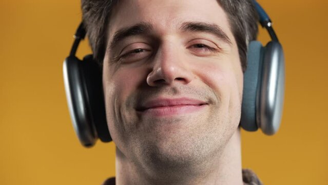 Close face of handsome man listening music,enjoying dance with modern headphones