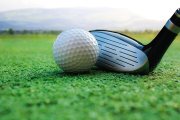 A golf ball is placed on the grass with a mountain view behind.