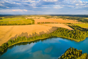 A landscape with yellow fields and a blue lake