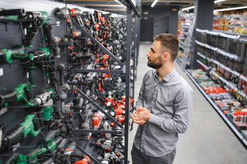 a buyer in a hardware store walks between with a power tool