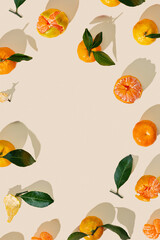 Frame of Tangerines as minimal style, juice fresh orange yellow fruits with green leaves on beige background. Citrus mandarines as still life food, flat lay, summer aesthetic photo, copy space